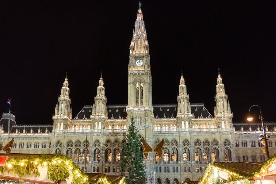 Otázka 25: Osvětlená gotická radnice s vysokou centrální věží nad tržními stánky v noci