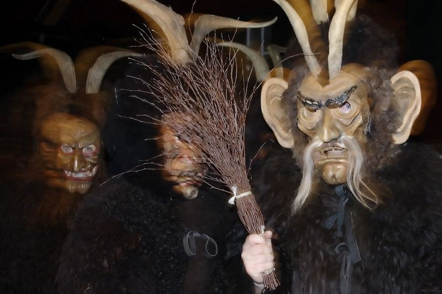 Otázka 49: Figury ve vyřezávaných dřevěných maskách s dlouhými rohy a huňatými kožichy, jedna držící svazek březových větviček