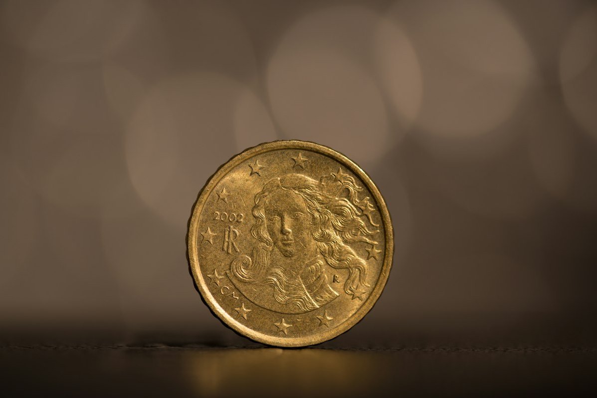 Egyetlen aranyérme áll a szélén egy sötét, elmosódott háttér előtt