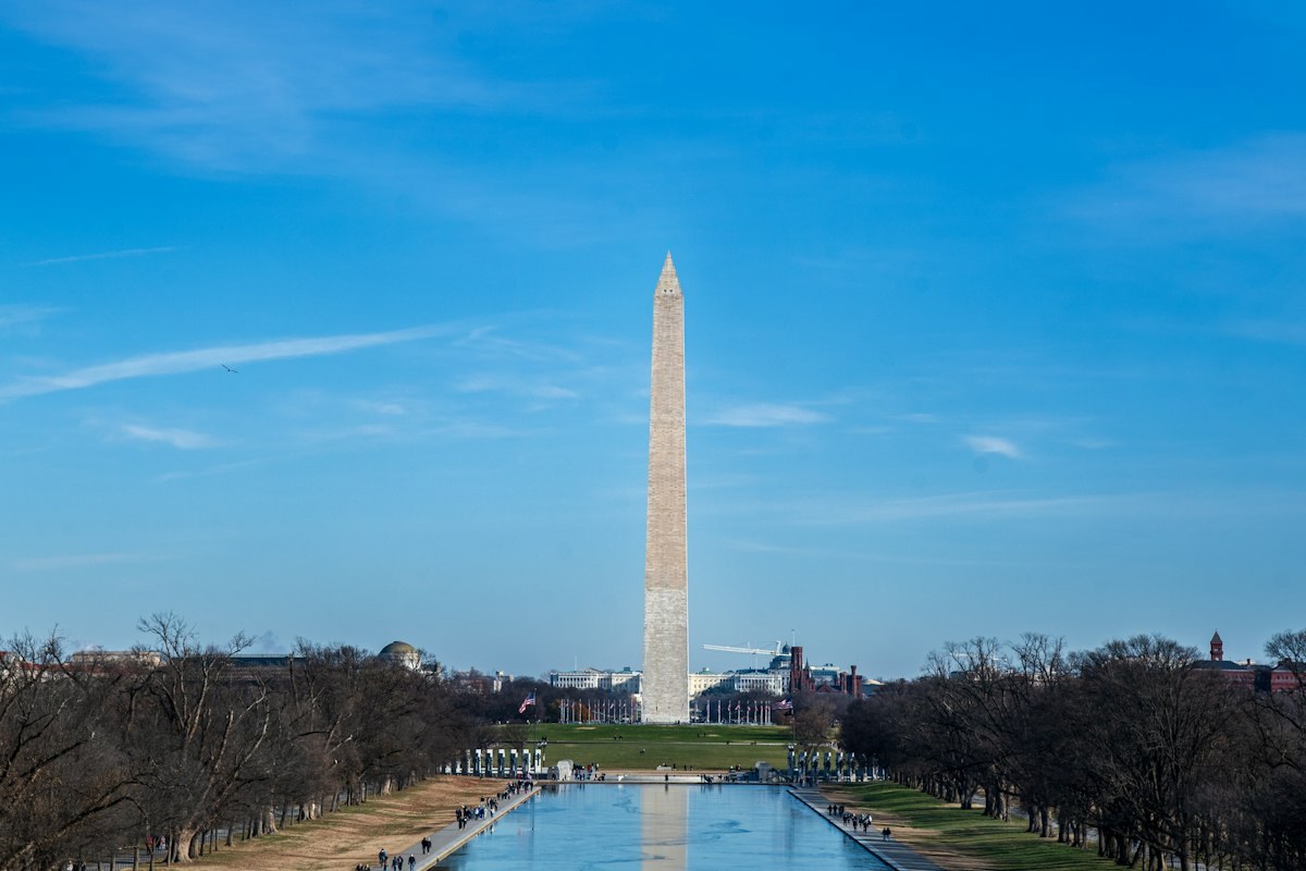 The Washington Monument rising above the Reflecting Pool under a blue sky