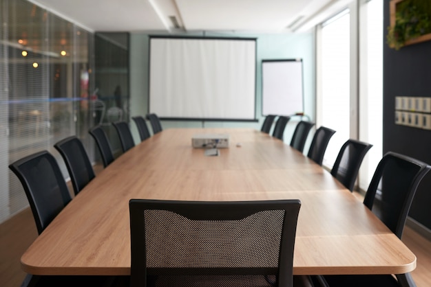 Salle de réunion avec table de conférence et écran de projection pour les réunions publiques
