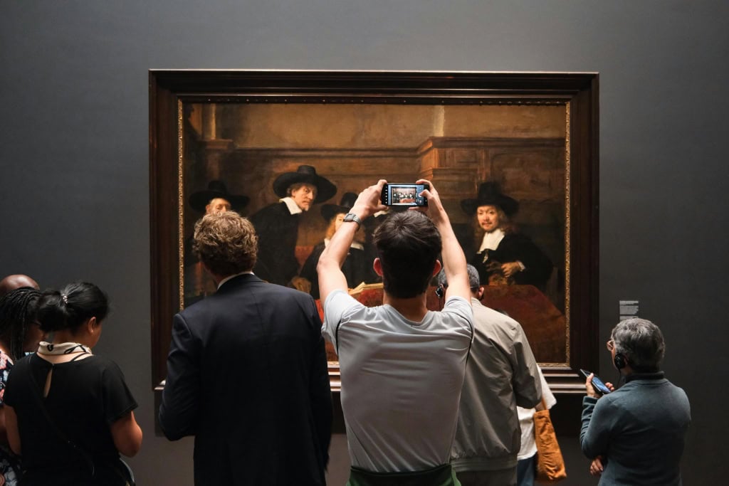 Un homme prend une photo d'une œuvre d'art.