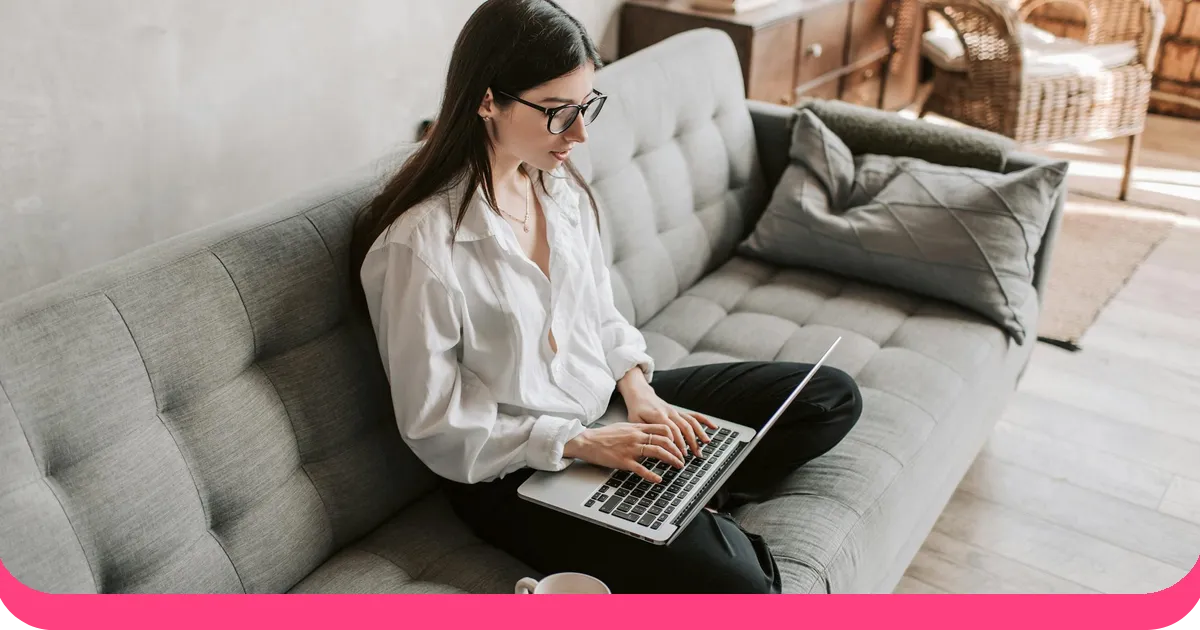 Professional writing a presentation on a laptop while sitting on a couch with coffee