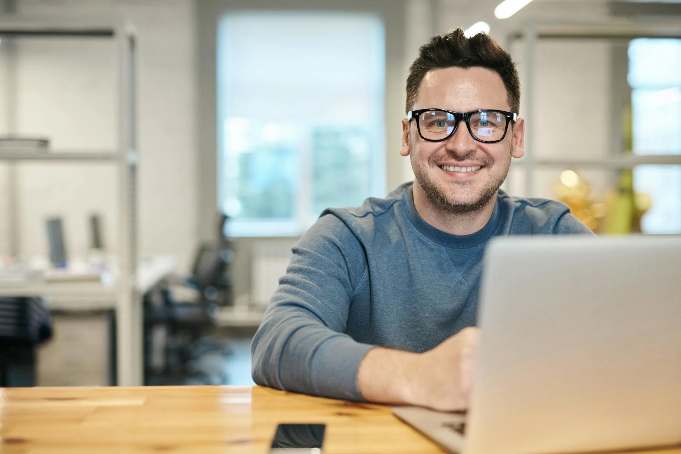 Professional smiling while working on a presentation at a laptop in a modern office