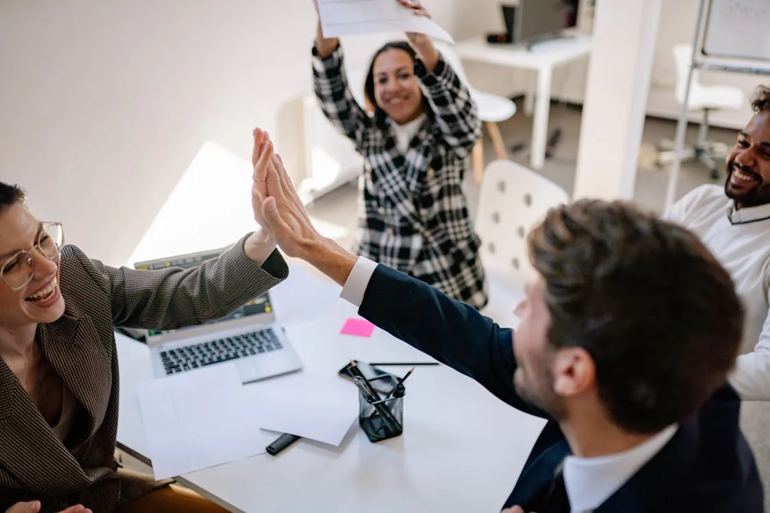 Coworkers giving a high five while celebrating at an office meeting