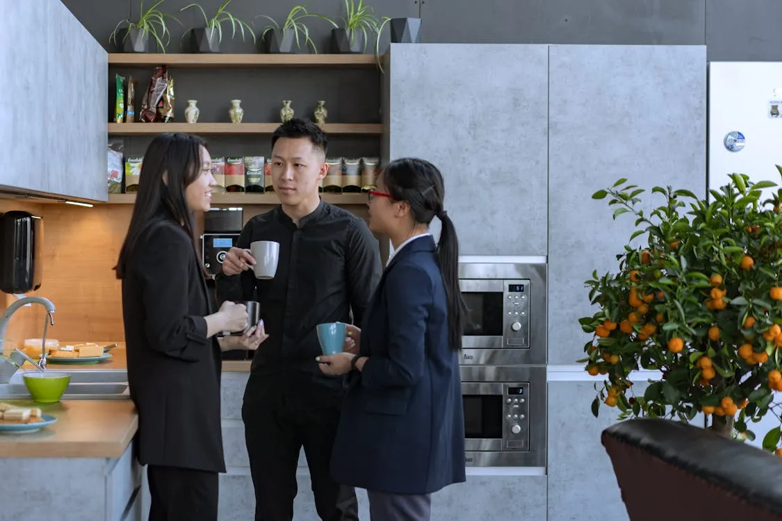 Three colleagues enjoying a coffee break in the office kitchen