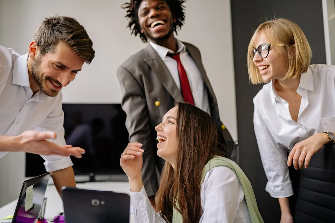 Colleagues smiling and laughing together at their desk in the office