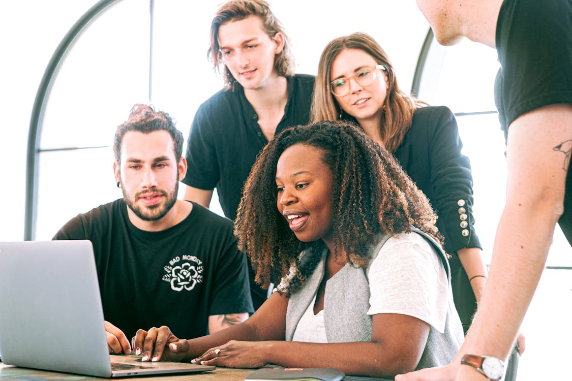 Group of colleagues collaborating together around a laptop in a modern workspace