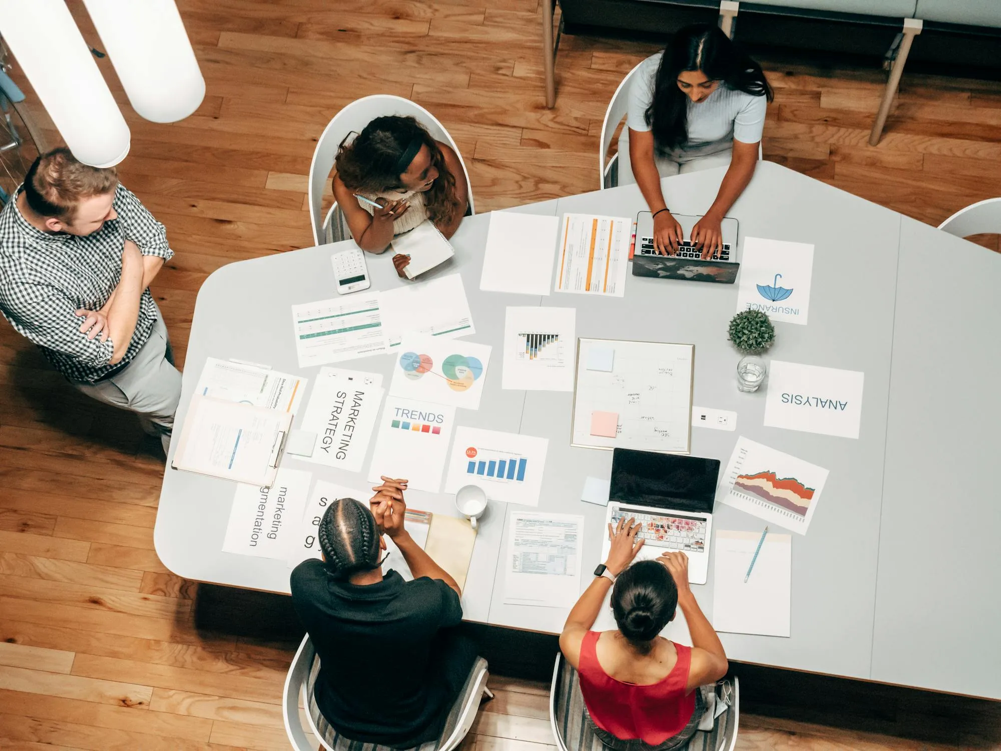 Draufsicht auf ein Marketingteam, das bei einem Meeting Umfrageanalysen und Trenddaten auswertet.