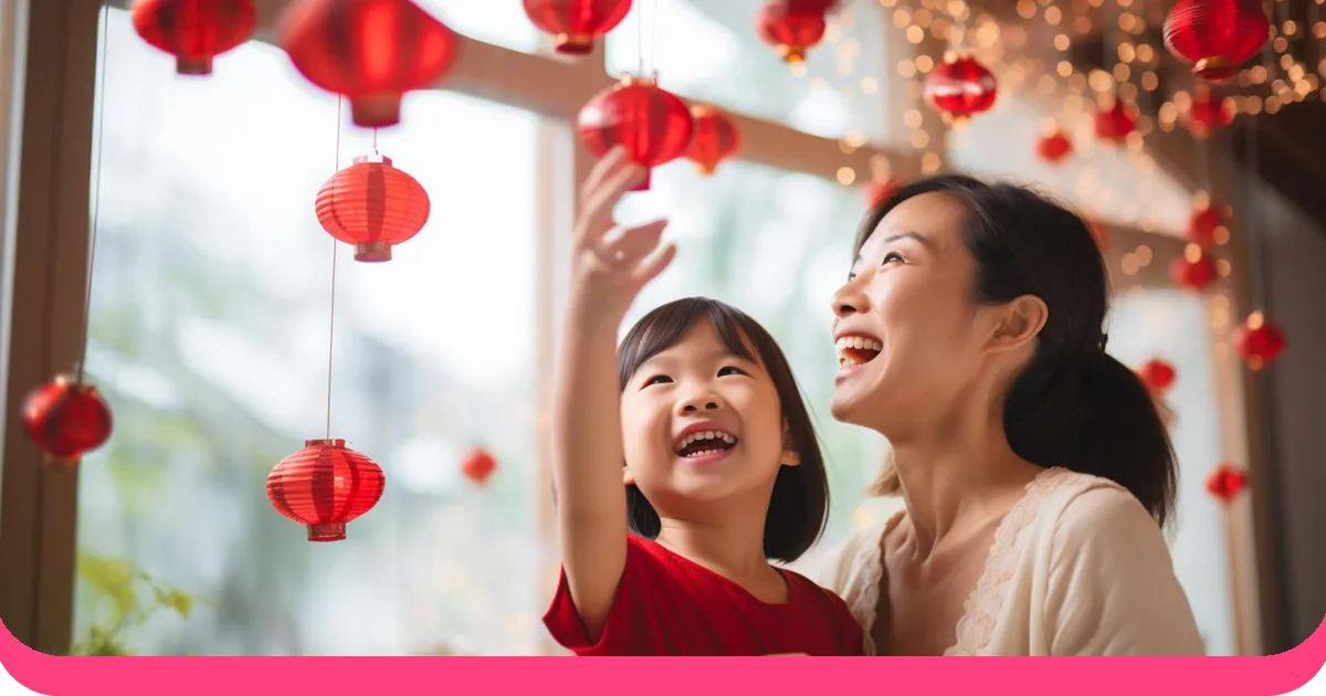Mãe e filha asiáticas pendurando lanternas vermelhas em casa para celebrar o Ano Novo Chinês.