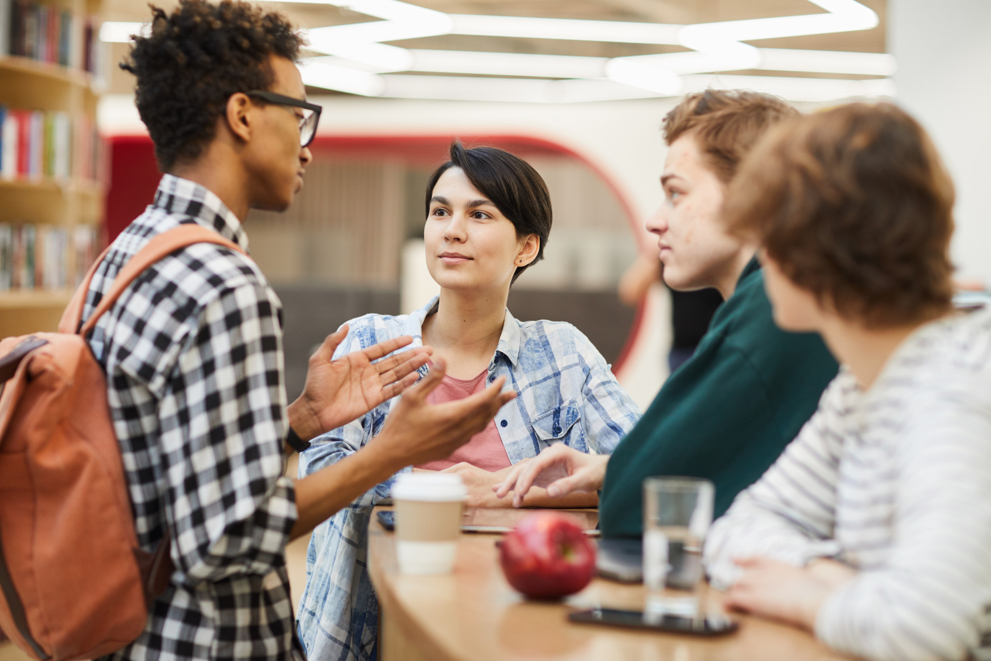 Group of high school students in discussion, one gesturing while making a point to classmates