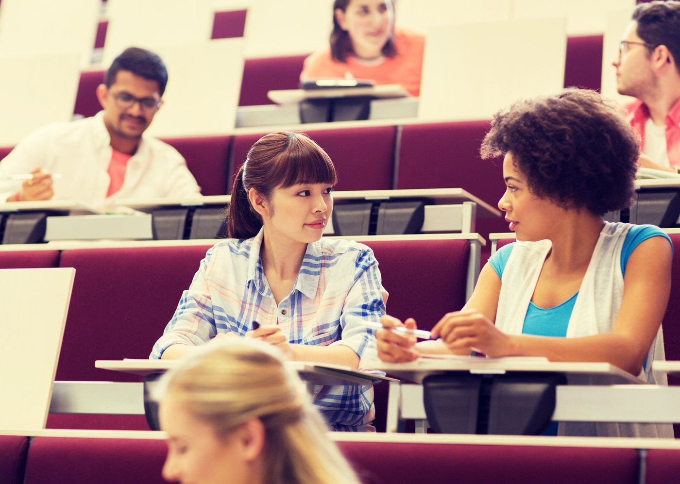 Divi universitātes studenti lekciju zālē apspriež atbildi