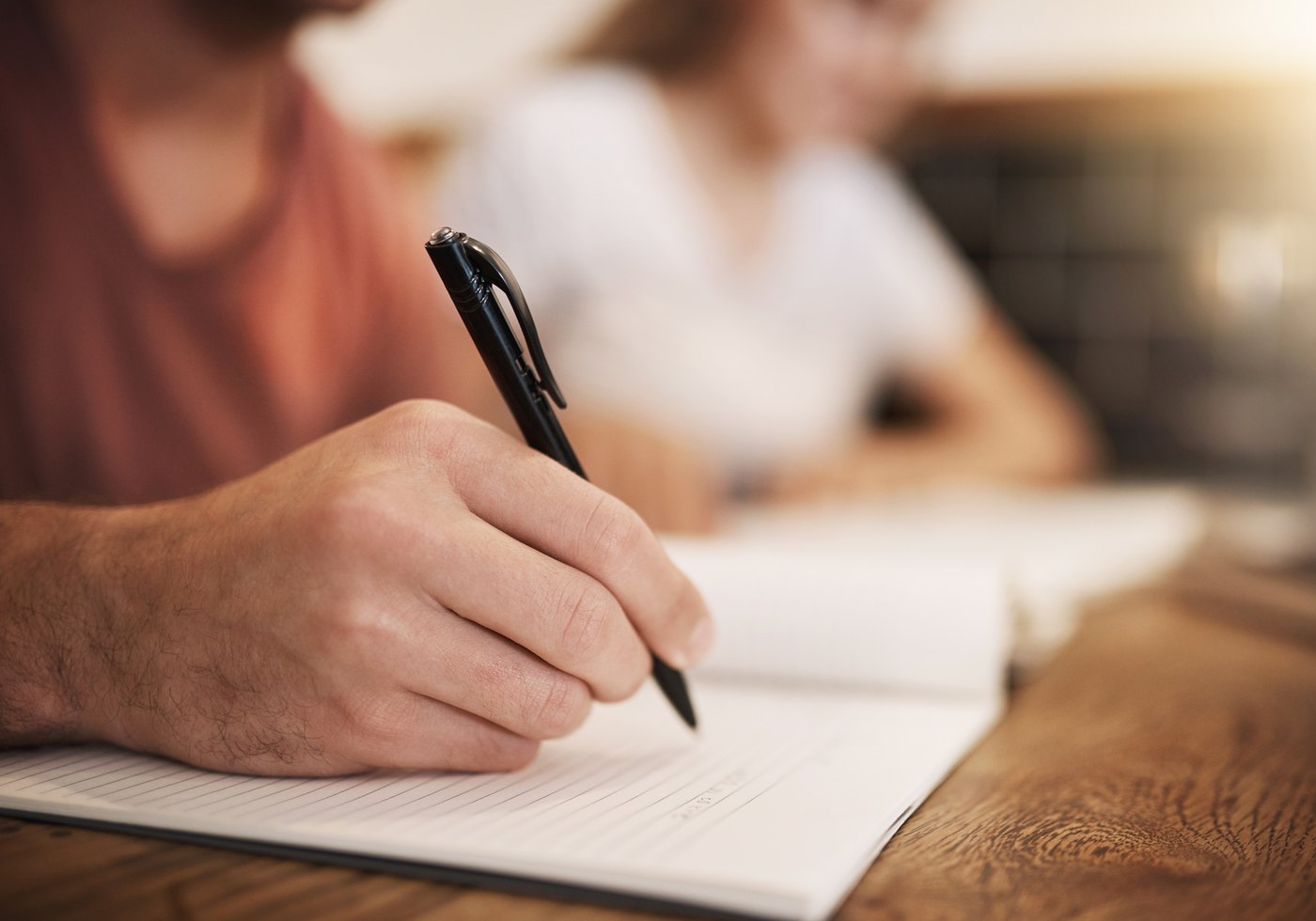 Ein Student schreibt einen Studienplan in ein Notizbuch