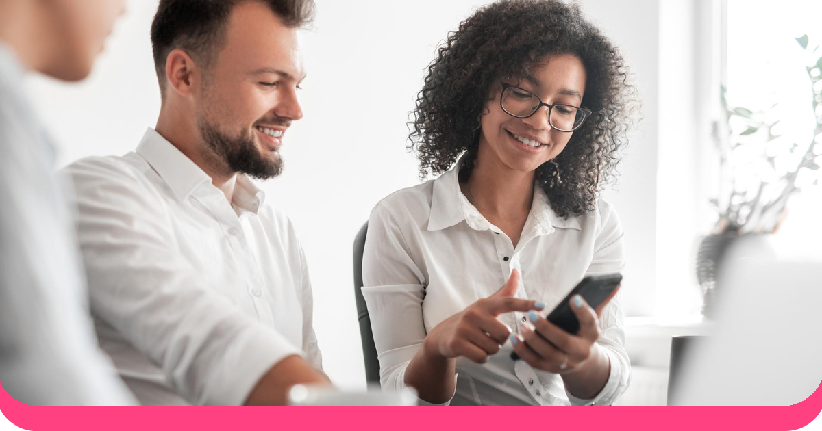 Happy coworkers laughing while looking at a smartphone together
