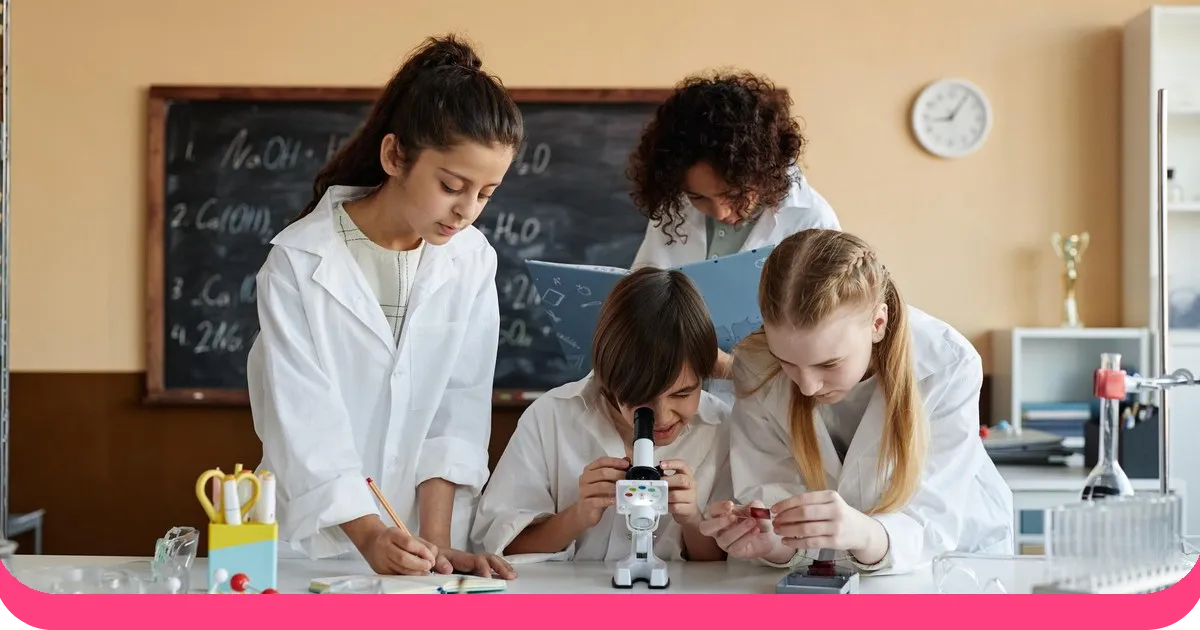 Students in lab coats investigating a sample under a microscope during a science class