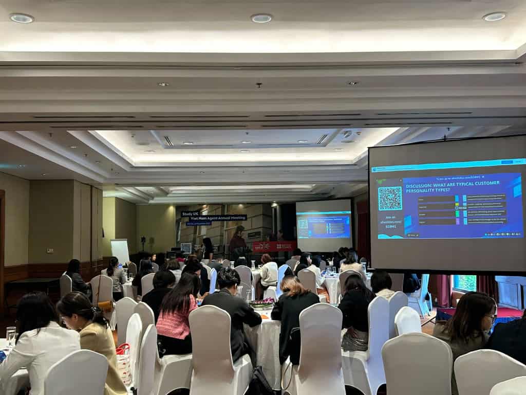 An event hall with seated attendees answering a discussion question on the big screen using AhaSlides