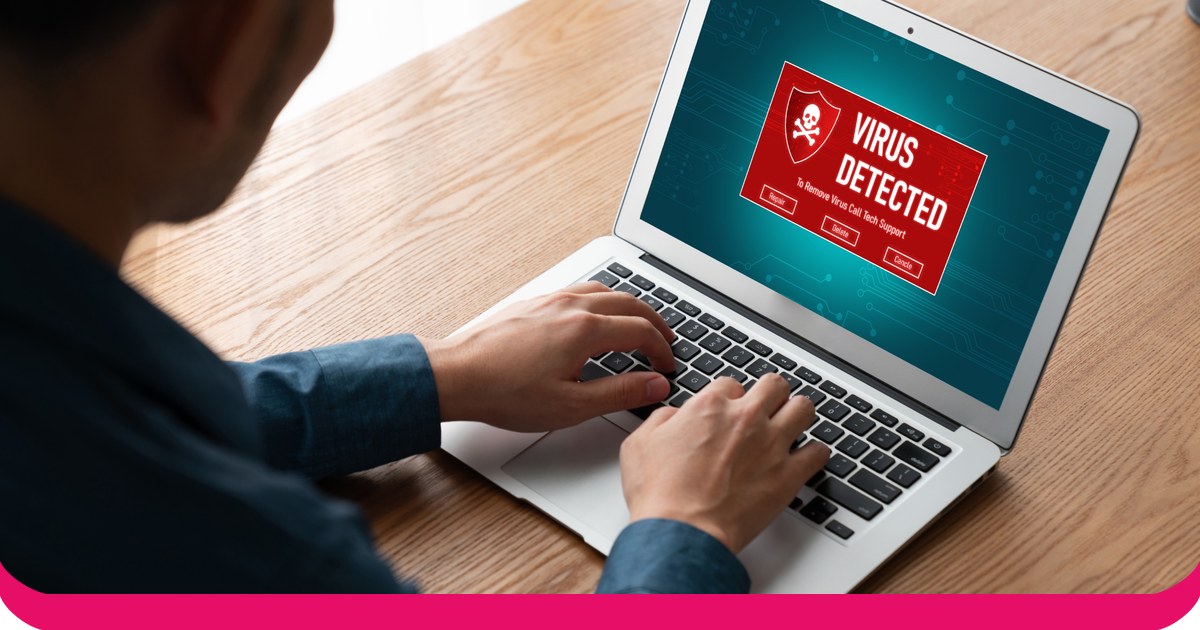 Una persona sta digitando su un computer portatile il cui schermo mostra un avviso di virus in rosso.