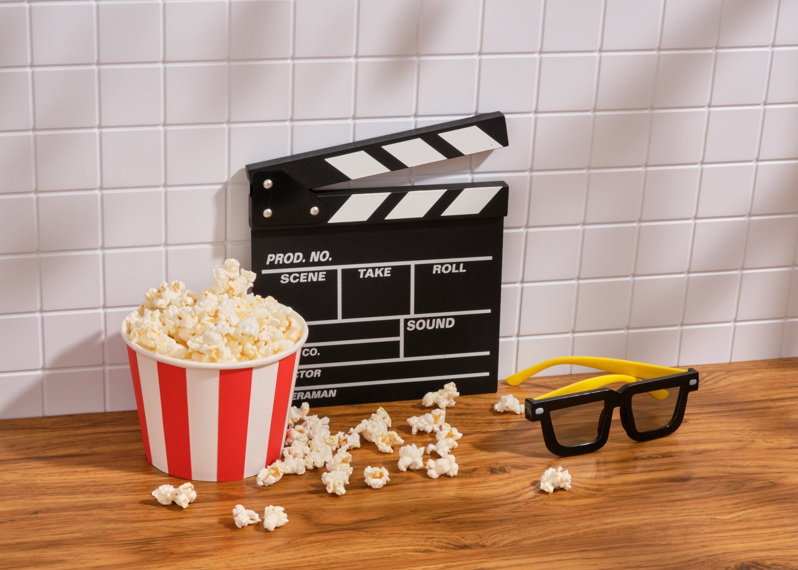 Film clapperboard sa tabi ng isang balde ng popcorn at isang pares ng 3D glasses