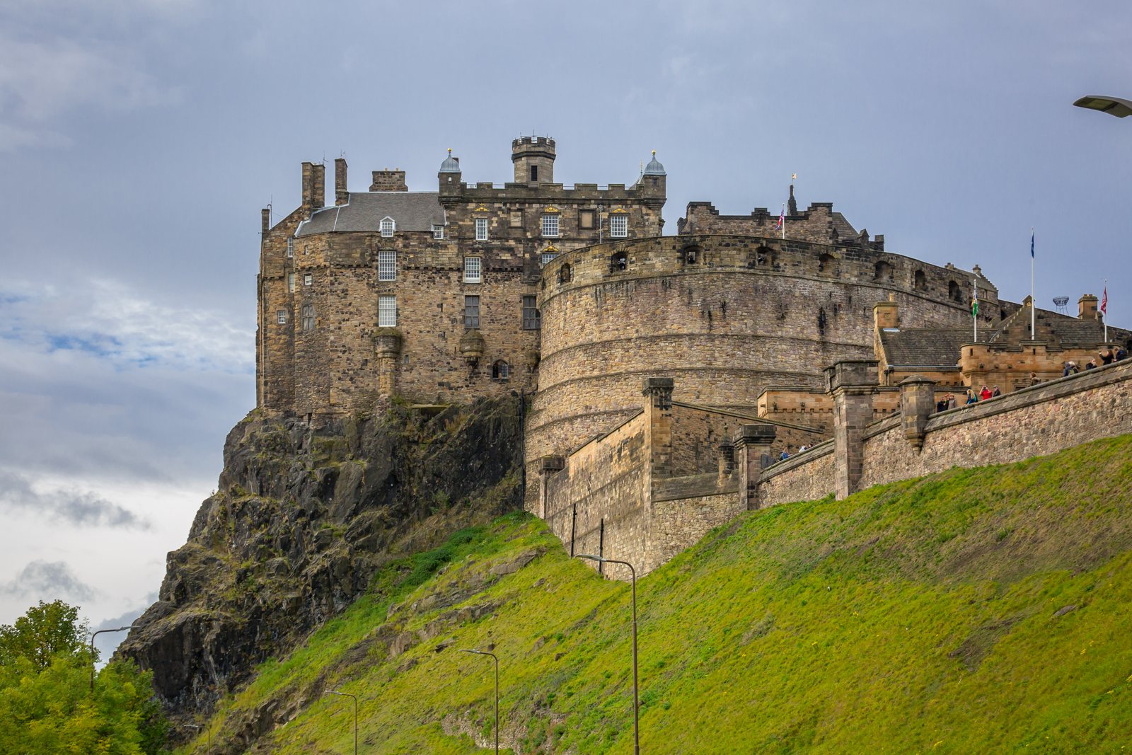 Edinburgh Castle, a stone fortress on a steep grassy rock under a cloudy sky