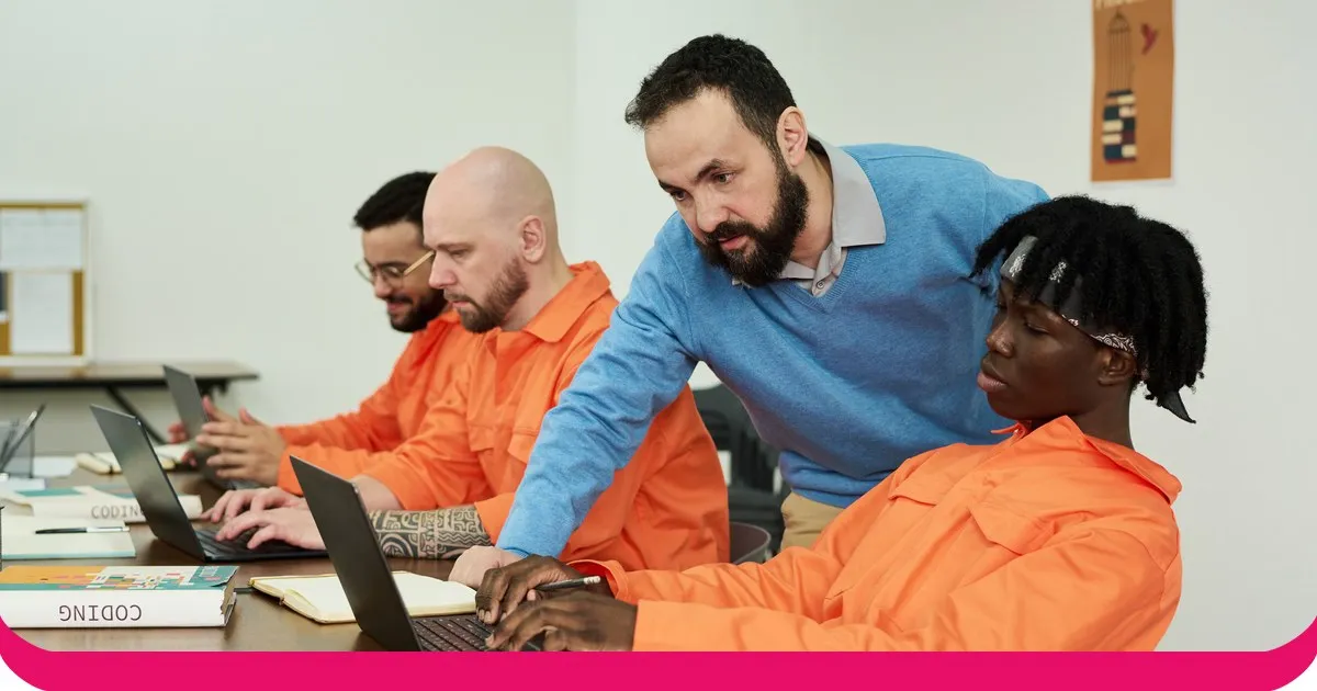 An instructor guiding a group of engineers learning to code on laptops