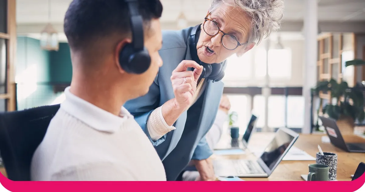 A sales leader coaching a headset-wearing rep at a desk during a call review
