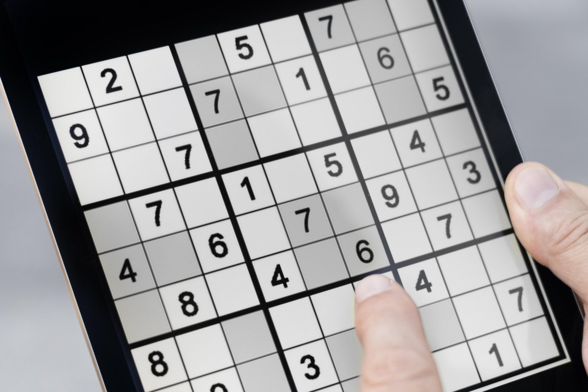 Prim-plan al unei persoane care joacă un puzzle sudoku pe o tabletă cu un deget pe ecran