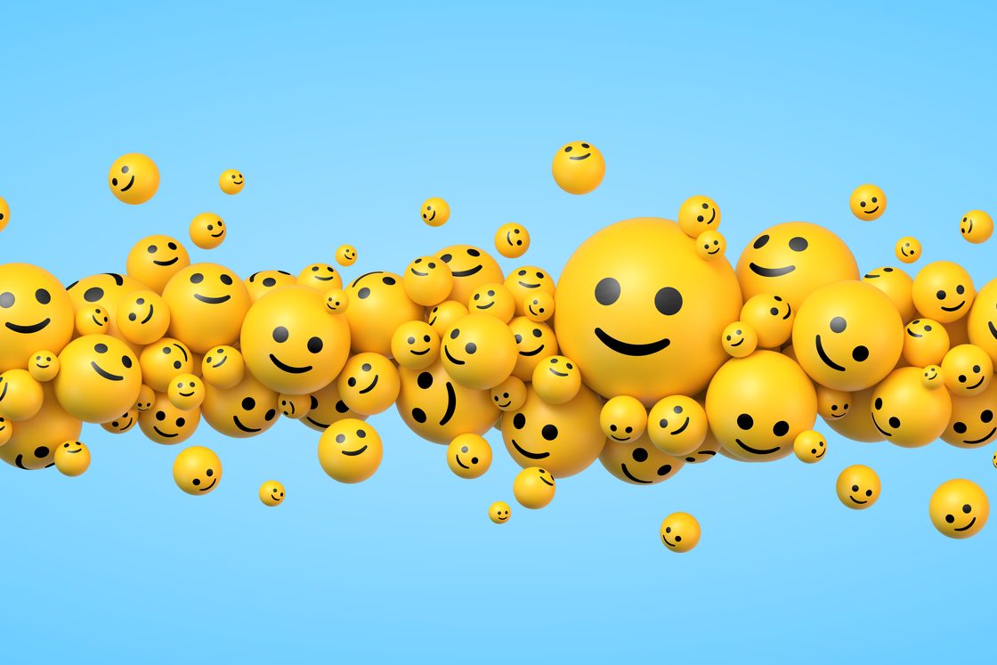 A cloud of yellow smiley-face balls in different sizes floating against a blue sky
