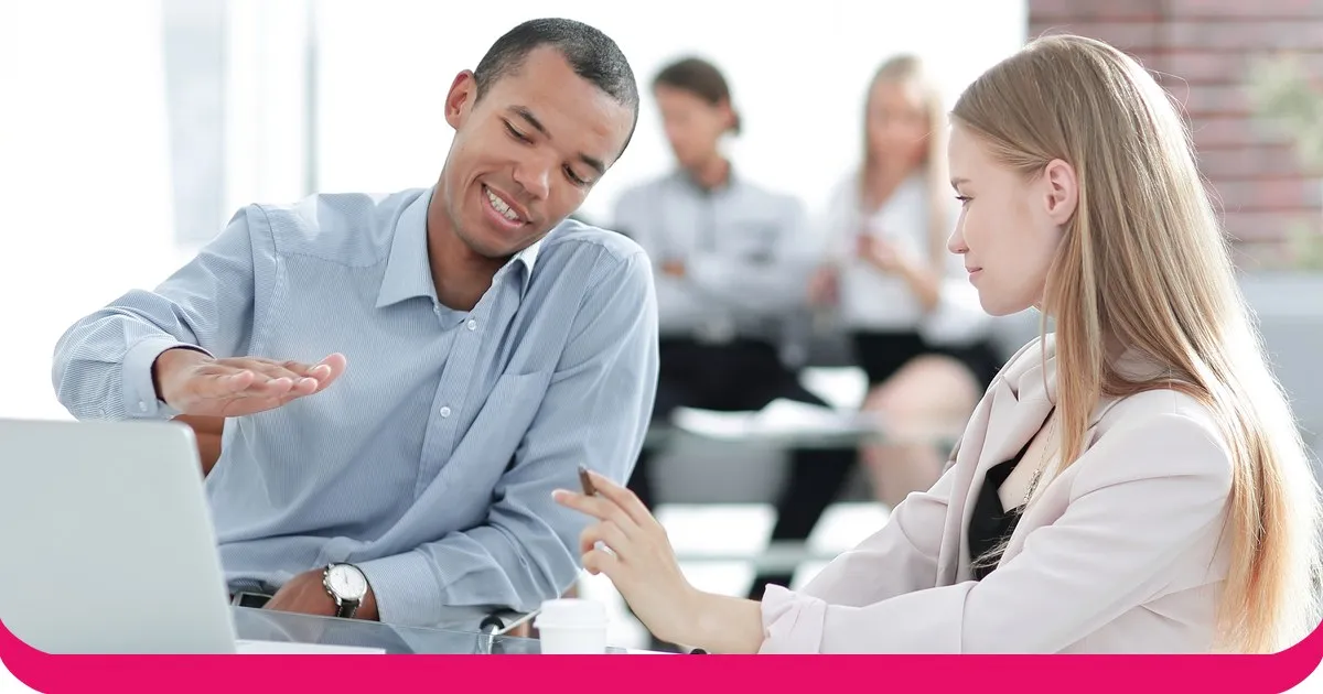 A sales manager talking through a plan with a colleague at a desk