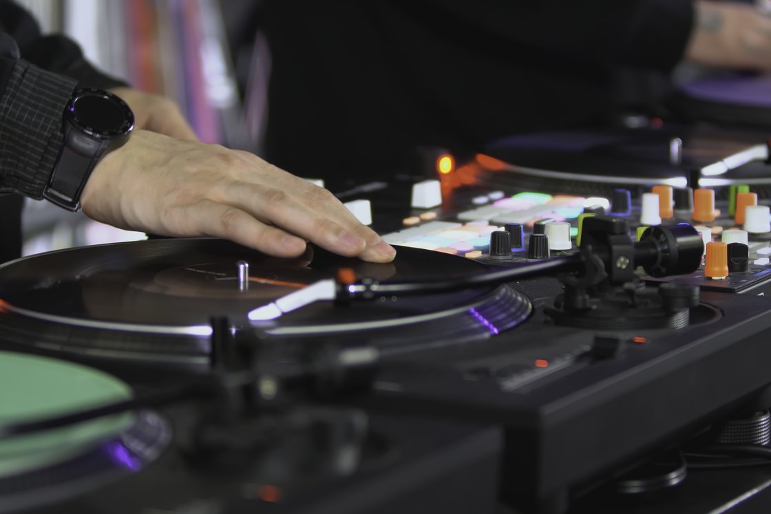 En DJs hånd på en platespiller og mikser, som spinner en plate