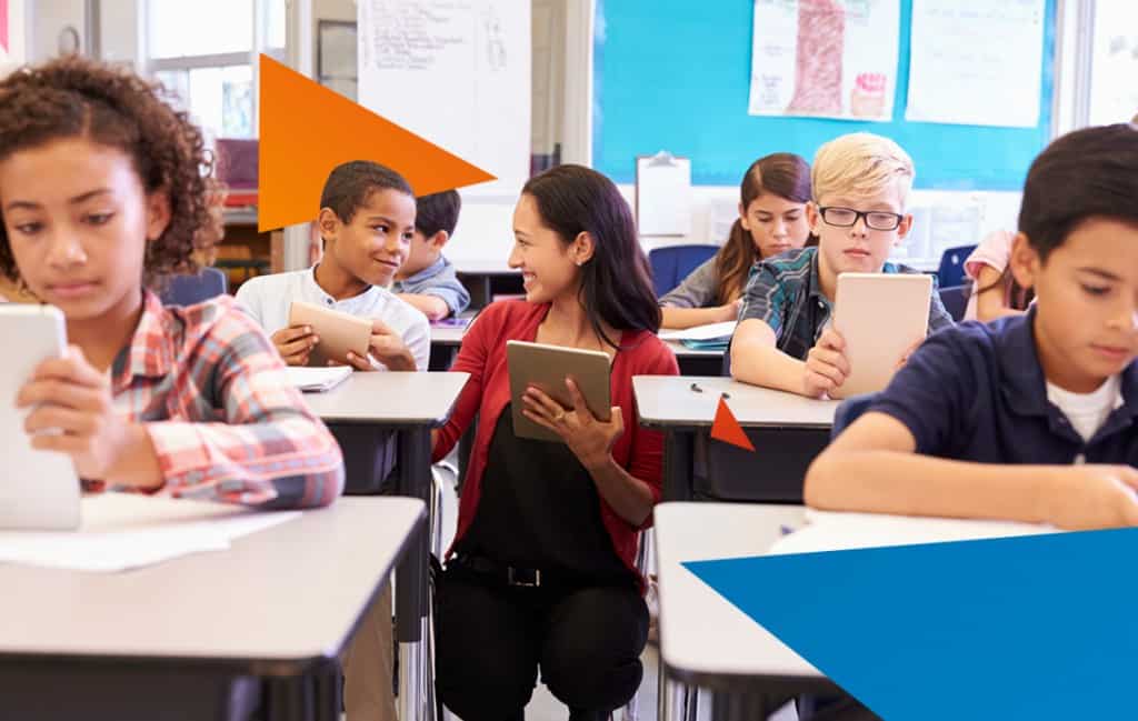 Teacher kneeling by a student to help him with his individual learning