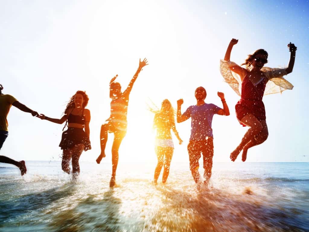 Group Of Young People At A Hot Summer Tropical Beach Party At Late