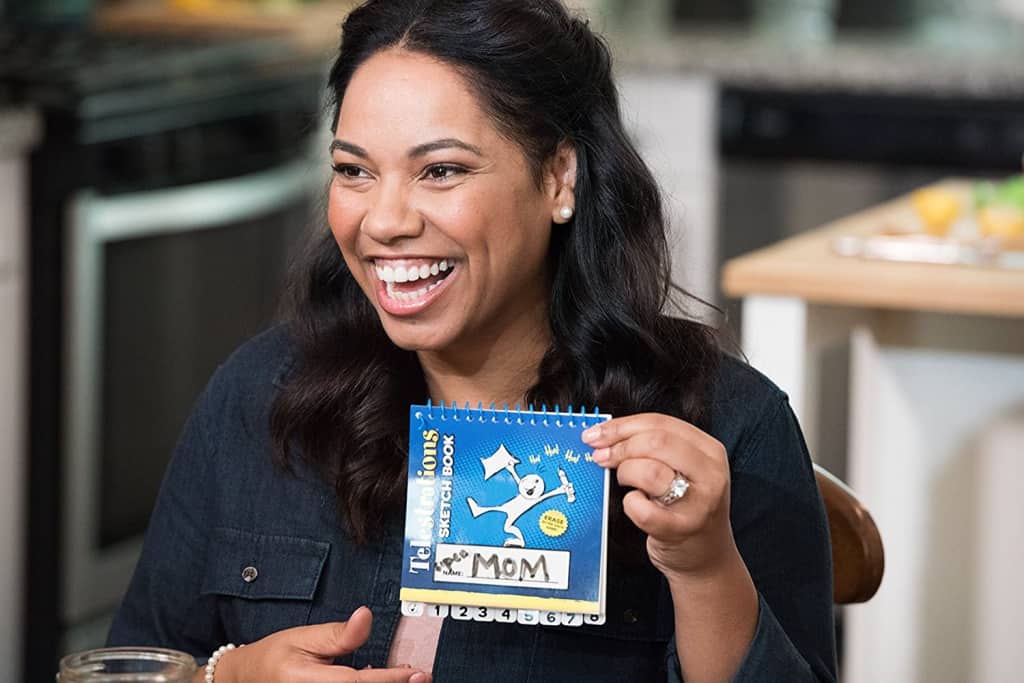 a woman showing a Telestrations game card in an adult dinner party